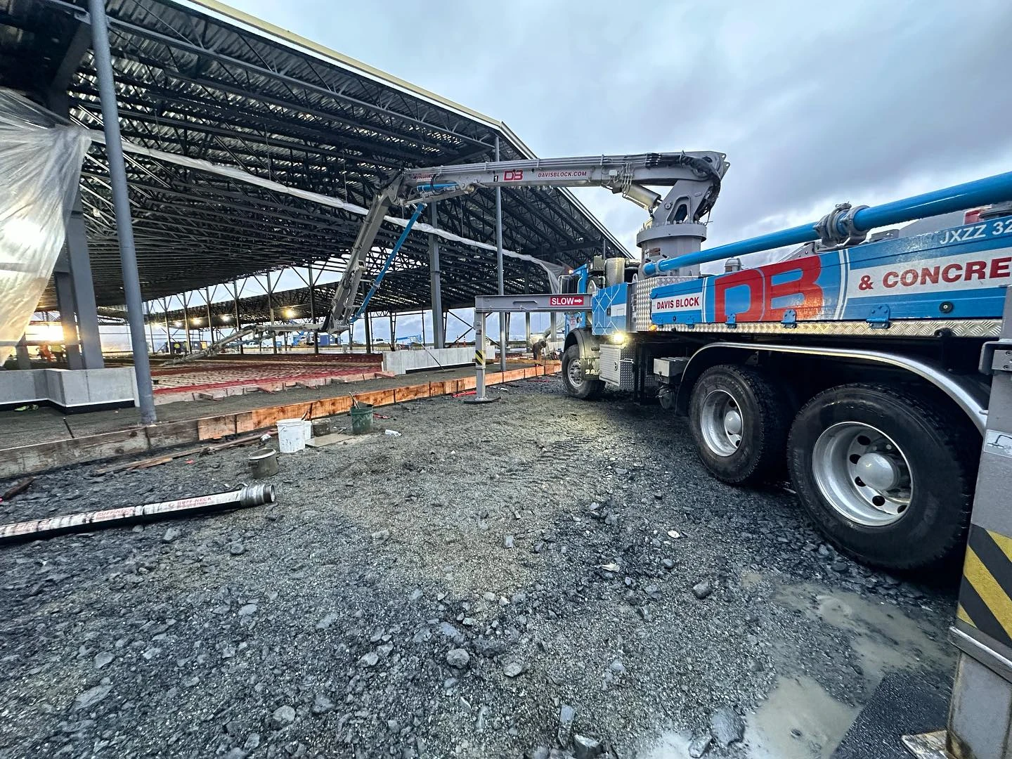 Davis Block boom pump truck (unit JXZZ 32) pouring large commercial slab at dusk
