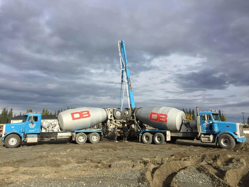 Two Davis Block mixer trucks flanking pump boom — symmetric shot