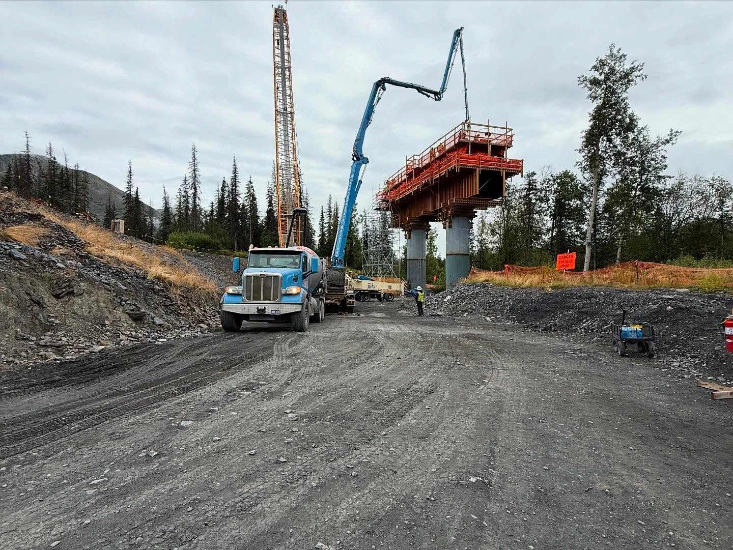 Wide-angle Juneau Creek Bridge construction site with crane and mixer fleet